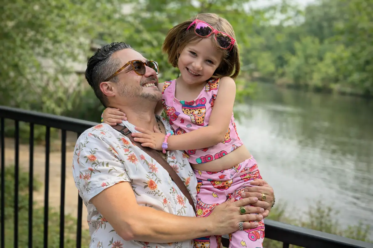 Johnny Tellez holding his daughter by a river